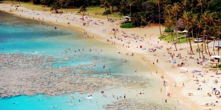Muchas personas disfrutando de una playa de aguas cristalinas en verano.