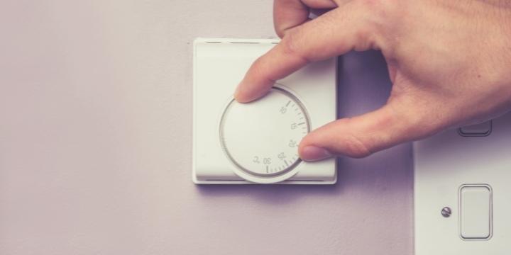 Persona encendiendo el termostato de su caldera para disfrutar de la calefacción en su hogar.